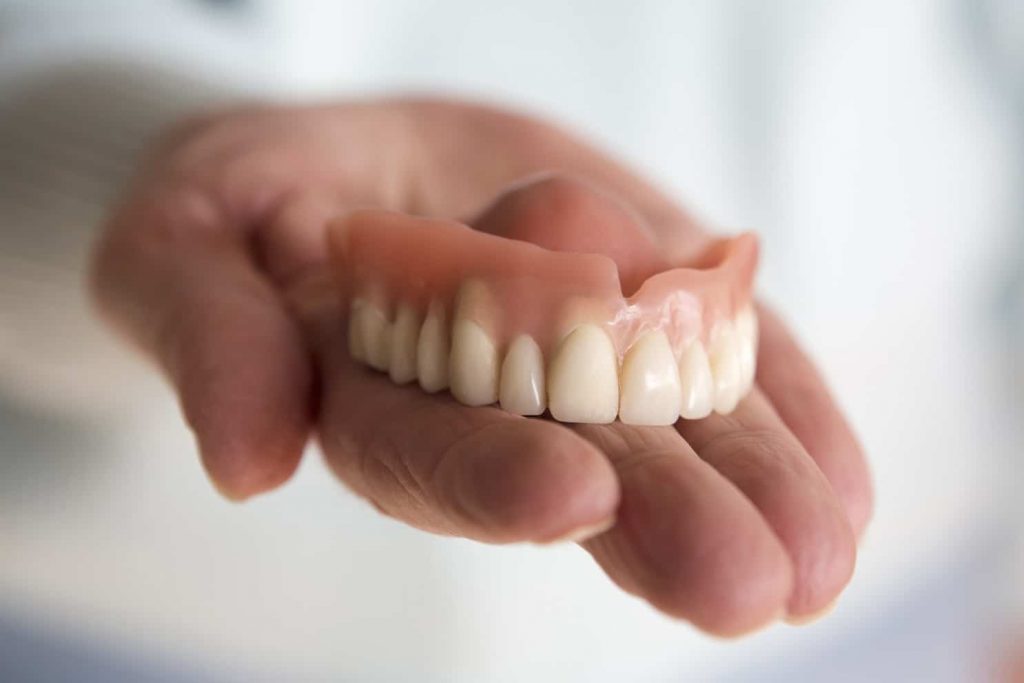 Woman holding top denture